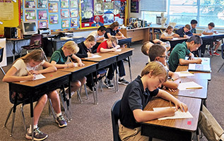 A full class practices cursive penmanship, which produces better writers.