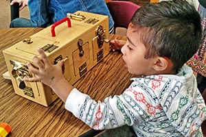 A toddler is taught to manipulate latches in one class.