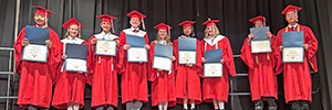Graduating Middle School students in cap and gown attire show their certificates of completion.