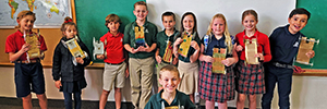 Students hold up their mousetrap cars, built for a science experiment.