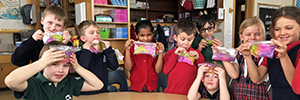 Young students hold up rainbow goo from a science experiment.